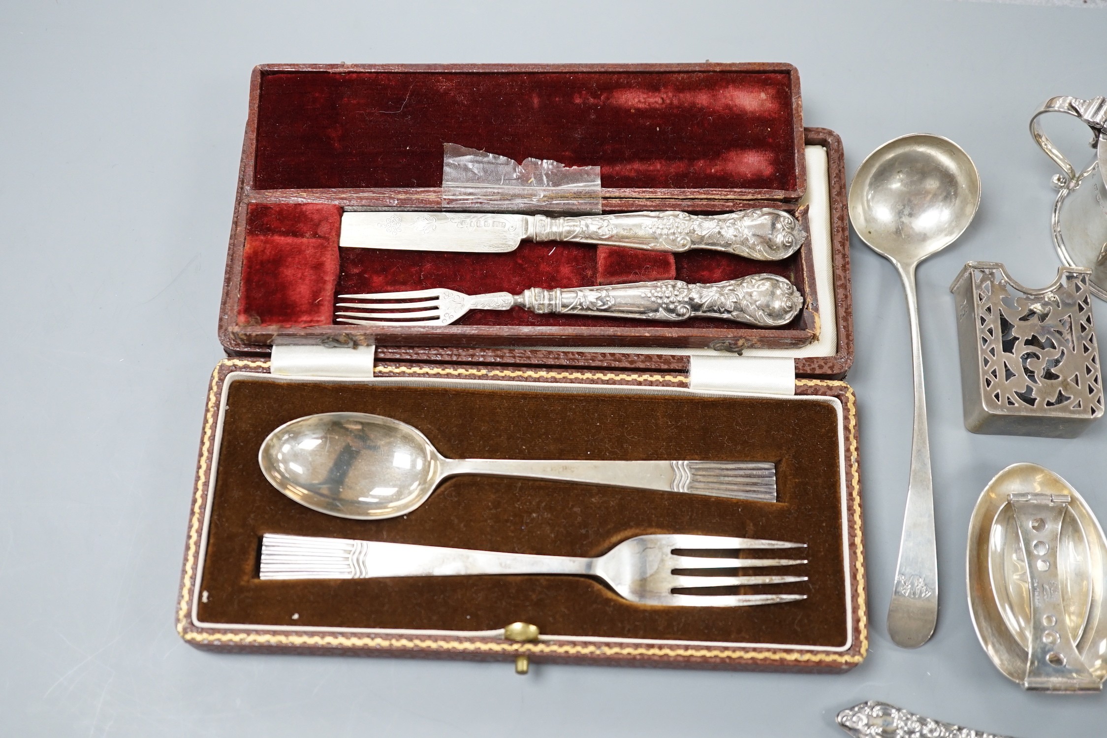 A small collection of sundry silver items including flatware, compact, cigarette case, mustard pot, sterling folding spoon, match sleeve, book mark, cased spoon and fork and a cased Victorian spoon and fork.